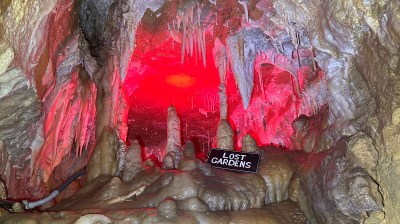 Cave with red lighting and stalactites, sign reads 'Lost Gardens'.