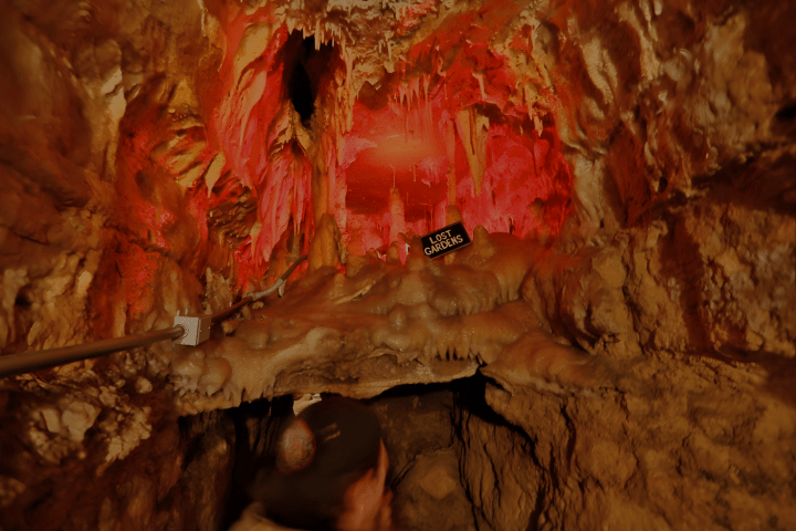 Cave interior with stalactites and red lighting.