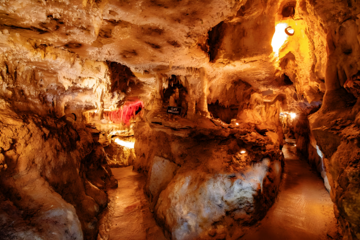 Illuminated cave with stalactites and rock formations.