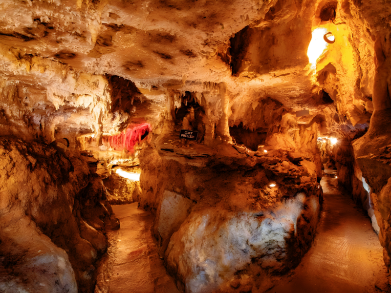 Illuminated cave with stalactites and rock formations.