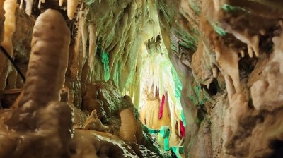 Stalactites and stalagmites in an illuminated cave passage.
