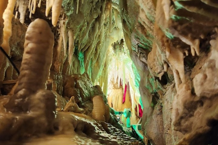 Stalactites and stalagmites in an illuminated cave passage.