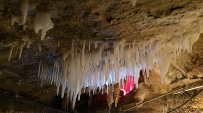 Stalactites hang from the cave ceiling with soft lighting in the background.